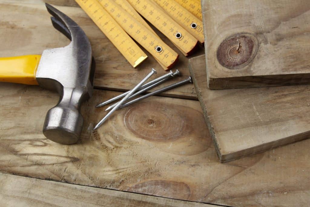 Hammer, nails and folding ruler on wood deck