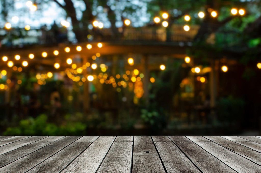 empty modern wooden terrace with abstract night light bokeh of night festival in garden, copy space for display of product or object presentation, vintage color tone