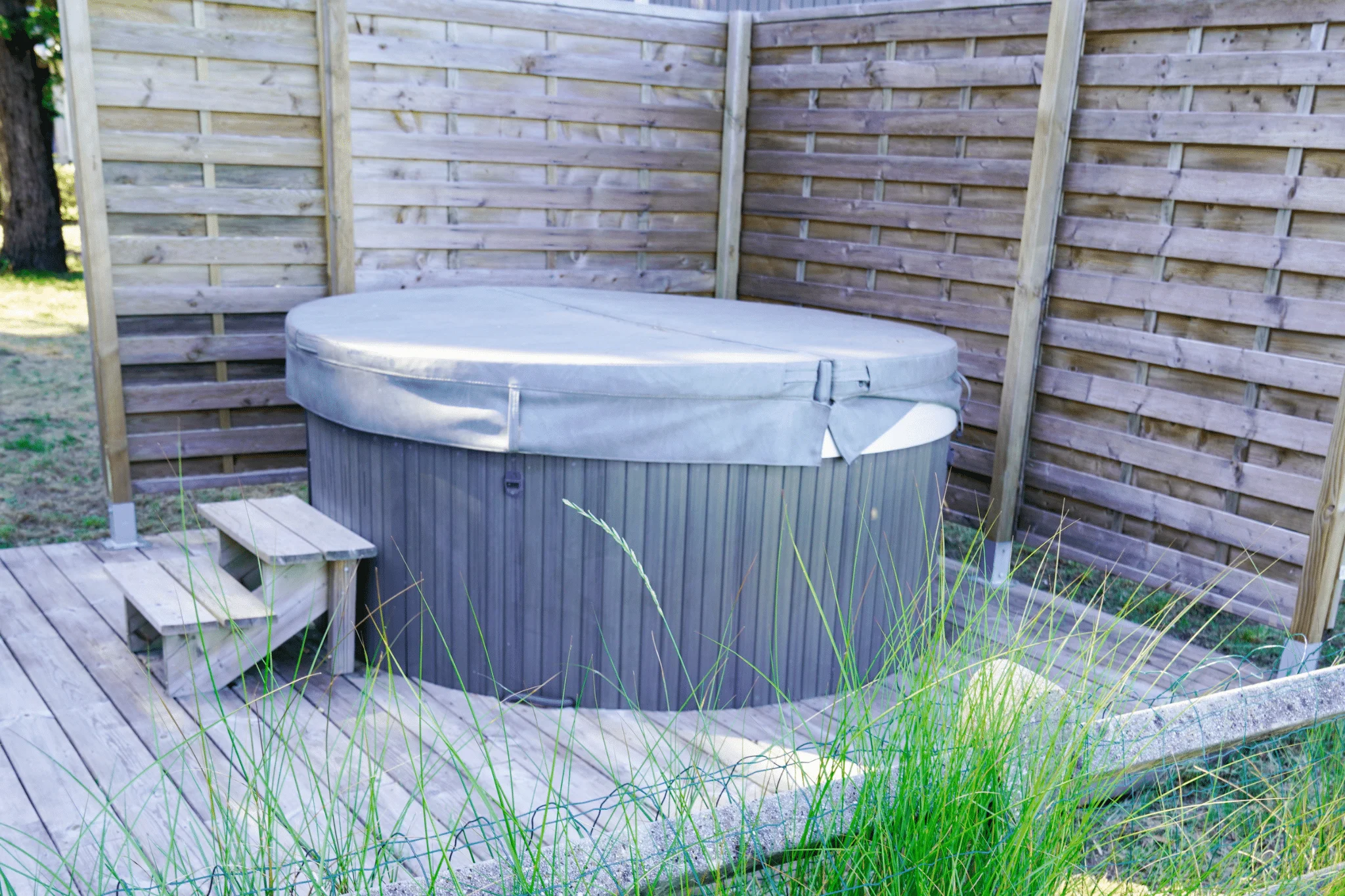A hot tub privacy enclosure made from a wooden fence.