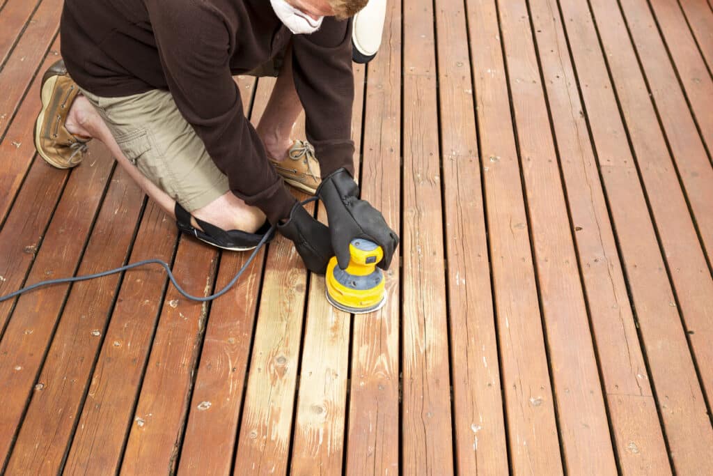 Mature man performing maintenance on home wooden deck